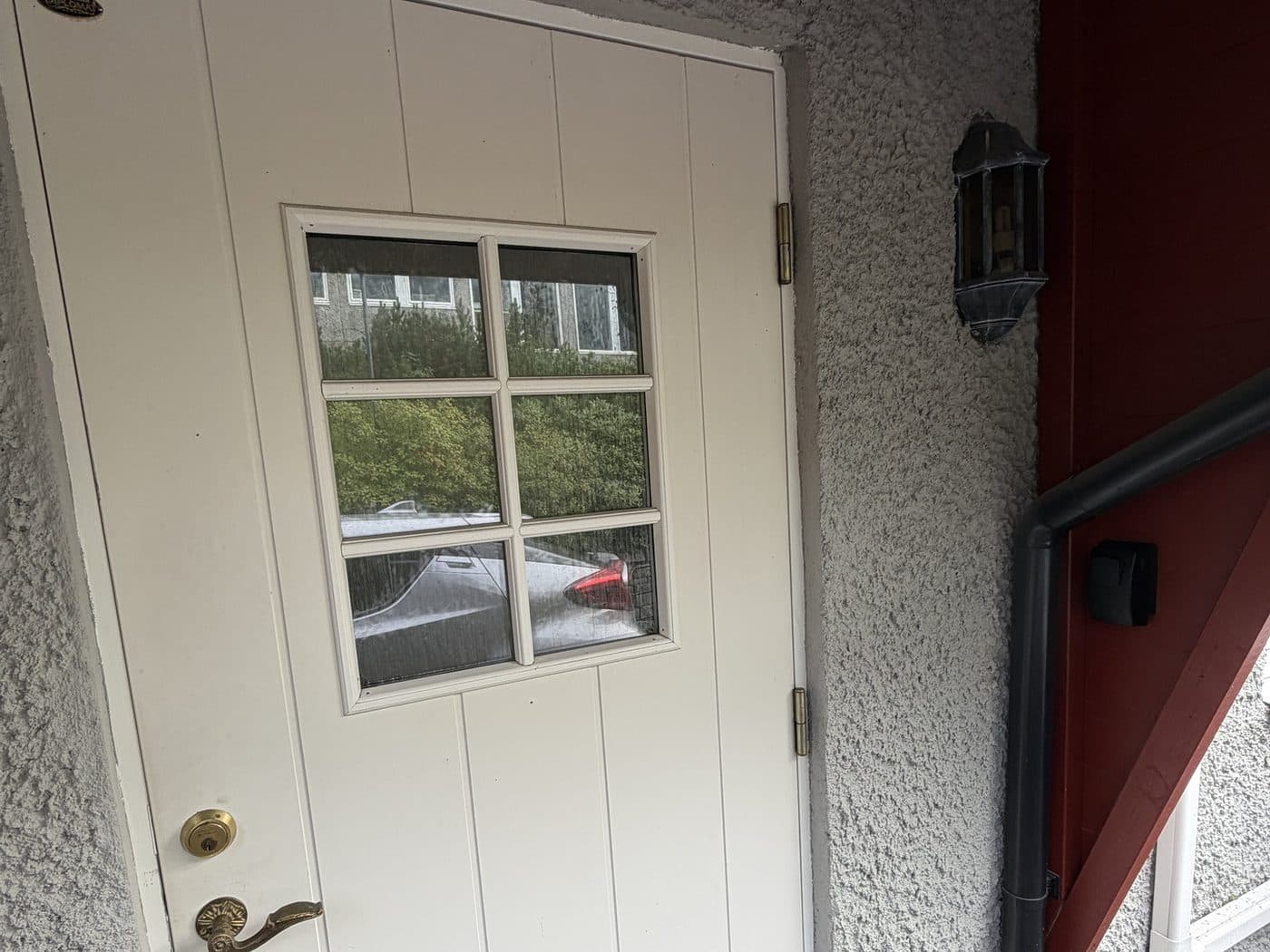 The white front door, with the black key box on the red wall to the right