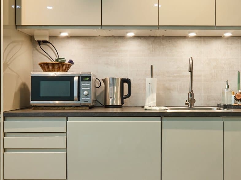 Close-up of the counter: microwave, kitchen towels and kettle