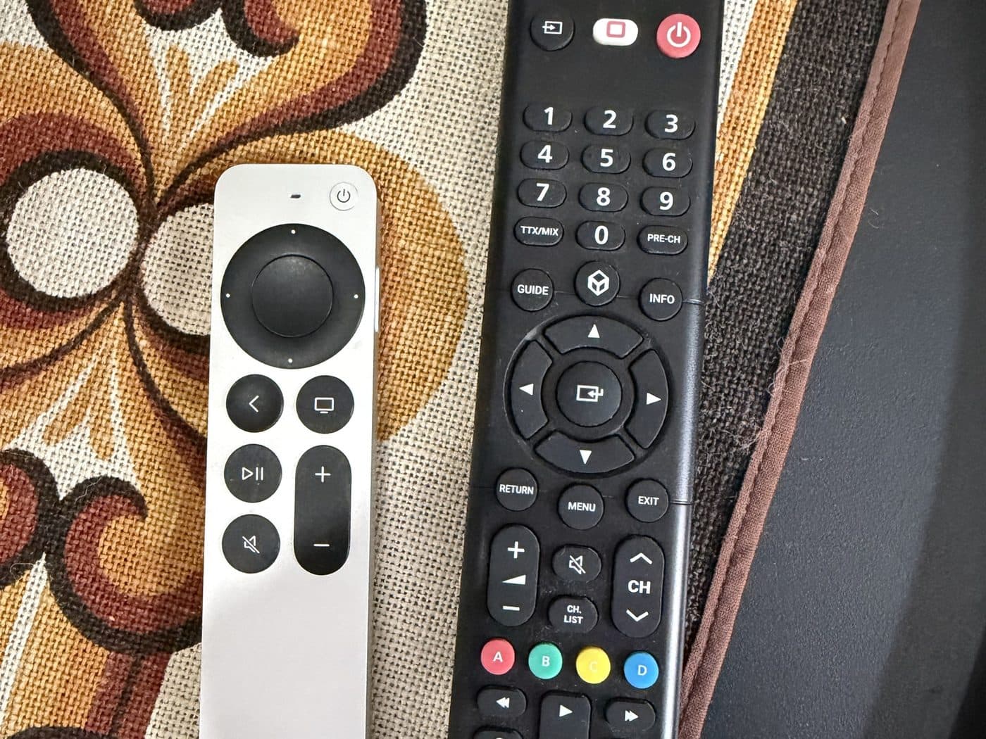The two remotes: silver for the Apple TV, black for the TV